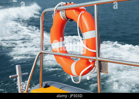 Red lifebuoy hanging on stern railings of fast motor boat Stockfoto