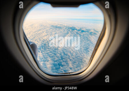 Aussicht aus dem Fenster eines Flugzeugs fliegen in Richtung Island. Durch das Fenster sehen Sie die Wolken über dem Meer vom Himmel. Stockfoto