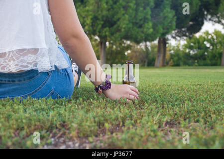 Mädchen unterstützt seine Bierflasche auf dem Boden, während am Horizont nachdenklich. Stockfoto