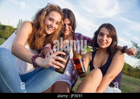 Die Mädchen genießen. Sie sind Freunde feiern den Urlaub eine gute Zeit Bier trinken in einem Park. Sie sind Toasten mit Flaschen. Stockfoto