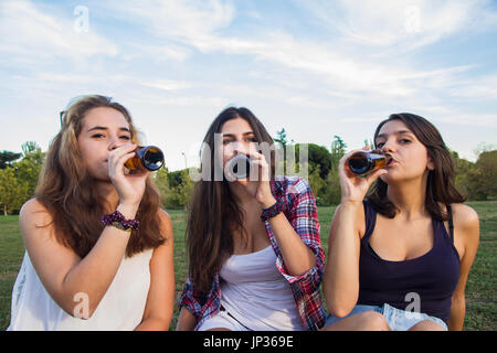 Weibliche Freunde feiern den Urlaub eine gute Zeit Bier trinken in einem Park. Sie sind glücklich. Die drei Mädchen trinken. Stockfoto