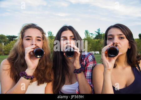 Weibliche Freunde feiern den Urlaub eine gute Zeit Bier trinken in einem Park. Sie sind glücklich. Die drei Mädchen trinken. Stockfoto