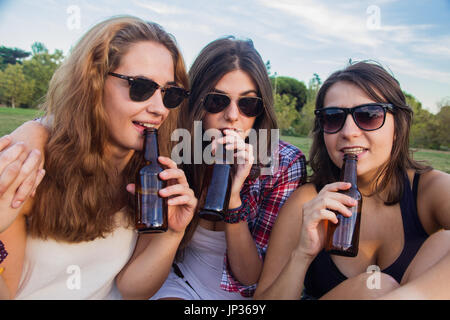 Weibliche Freunde feiern den Urlaub eine gute Zeit Bier trinken in einem Park. Sie sind glücklich. Die drei Mädchen trinken. Stockfoto