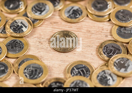 1-Dollar-Münzen in der Mitte mehrere 1-real-Münzen auf einem Holztisch Stockfoto