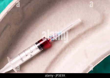 Medizinische Spritze mit Bloodsample liegen in einer Kapsel eine Verwendung auf grünem Hintergrund des Krankenhauses. Der Hintergrund kann eine Textile gehören eines Arztes oder nu Stockfoto