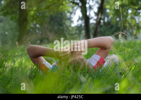 Junge liegend auf dem Rasen im Freien im Sommerpark Stockfoto