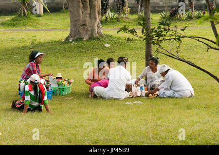 Ubud, Bali, Indonesien - 27. Juli 2013. Familien genießen ein Picknick beim Essen und trinken in einem Park im freien - Rhe Gras Stockfoto