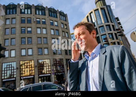 Aussehen des mittleren Alters Geschäftsmann stand vor dem Bürogebäude während des Gesprächs auf seinem Handy hautnah Stockfoto