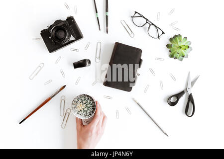 Teilweisen Draufsicht der menschlichen Hand, die Kakteen und verschiedene Büroartikel und Pflanze isoliert auf weiss Stockfoto