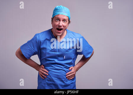 Einen glücklich mittleren gealterten männlichen Arzt stehend in blauen Peelings und lachen Stockfoto