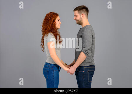 A beautiful young couple standing face to face and holding each others hands Stockfoto