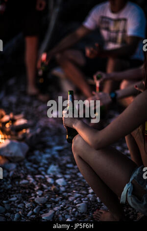 Eine Gruppe junger Menschen versammelten sich am Strand um ein Lagerfeuer. Stockfoto