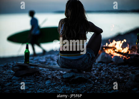 Eine Gruppe junger Menschen versammelten sich am Strand um ein Lagerfeuer. Stockfoto