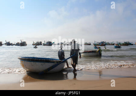 Mui Ne, Vietnam - 27. Juni 2017: Überfüllten Szene tägliche morgendliche Fischmarkt am Strand mit den Fischern auf Runde Boot Stockfoto