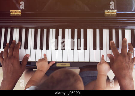 Kleinkind mit Vater Klavier spielen lernen Stockfoto