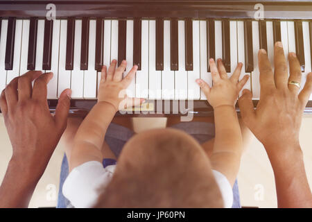 Kleinkind mit Vater Klavier spielen lernen Stockfoto