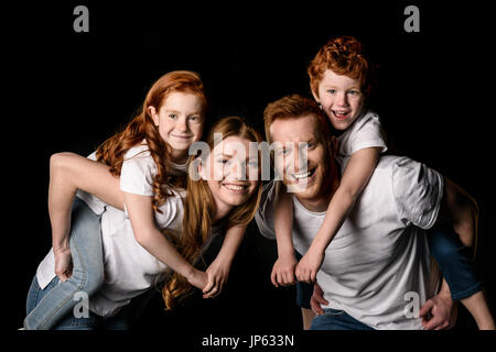 Glücklich Rotschopf Familie in weißen T-shirts lächelnd isoliert auf schwarz Stockfoto