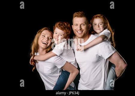 Glücklich Rotschopf Familie in weißen T-shirts lächelnd isoliert auf schwarz Stockfoto