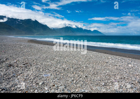 Dem azurblauen Wasser des Pazifischen Ozeans über die Kieselsteine, zentrale Bergkette im Hintergrund, Chisingtan Scenic Area, Hualien, Taiwan Stockfoto