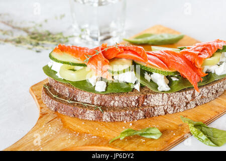 Sandwich mit geräuchertem Lachs, Gemüse und Quark auf einem Holzbrett. Stockfoto