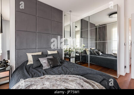 Luxuriöse Schlafzimmer mit verspiegelten Kleiderschrank, Doppelbett und gepolsterte Wand Stockfoto