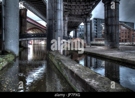 Dunkel und düster und Industrieatmosphäre unter den historischen Eisenbahnbrücken in Manchester Stockfoto