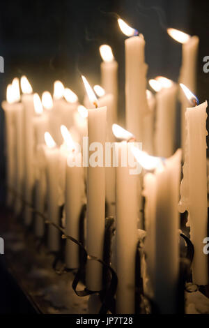 Vertikale Nahaufnahme von Reihen von votive Kerzen brennen in einer Kirche. Stockfoto