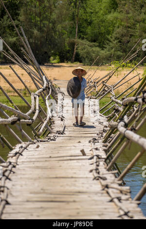 Vietnamesische Mann zu Fuß über eine traditionelle Bambusbrücke in ländlichen Vietnam Stockfoto