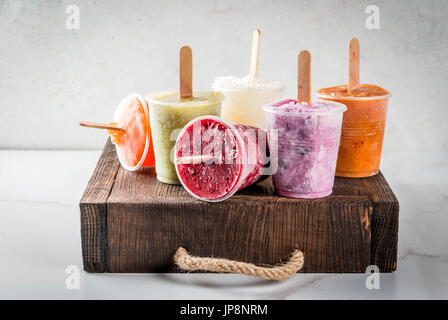 Gesunden Sommer Desserts. Eis Eis am Stiel. Gefrorene tropische Säfte, Smoothies Blaubeeren. Johannisbeere, Orange, Mango, Kiwi, Banane, Kokos, Himbeere Stockfoto