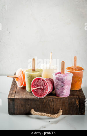 Gesunden Sommer Desserts. Eis Eis am Stiel. Gefrorene tropische Säfte, Smoothies Blaubeeren. Johannisbeere, Orange, Mango, Kiwi, Banane, Kokos, Himbeere Stockfoto