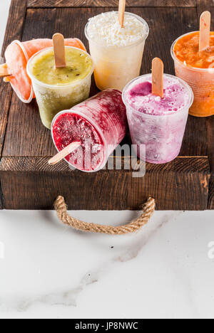 Gesunden Sommer Desserts. Eis Eis am Stiel. Gefrorene tropische Säfte, Smoothies Blaubeeren. Johannisbeere, Orange, Mango, Kiwi, Banane, Kokos, Himbeere Stockfoto