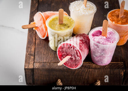 Gesunden Sommer Desserts. Eis Eis am Stiel. Gefrorene tropische Säfte, Smoothies Blaubeeren. Johannisbeere, Orange, Mango, Kiwi, Banane, Kokos, Himbeere Stockfoto