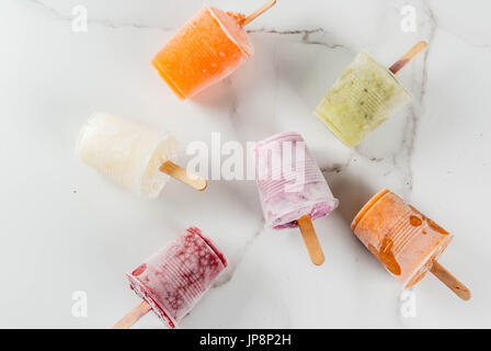 Gesunden Sommer Desserts. Eis Eis am Stiel. Gefrorene tropische Säfte, Smoothies Blaubeeren. Johannisbeere, Orange, Mango, Kiwi, Banane, Kokos, Himbeere Stockfoto