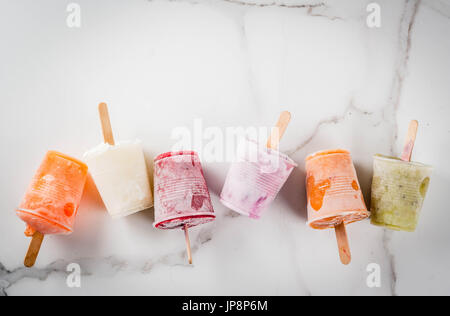 Gesunden Sommer Desserts. Eis Eis am Stiel. Gefrorene tropische Säfte, Smoothies Blaubeeren. Johannisbeere, Orange, Mango, Kiwi, Banane, Kokos, Himbeere Stockfoto