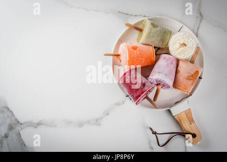 Gesunden Sommer Desserts. Eis Eis am Stiel. Gefrorene tropische Säfte, Smoothies Blaubeeren. Johannisbeere, Orange, Mango, Kiwi, Banane, Kokos, Himbeere Stockfoto
