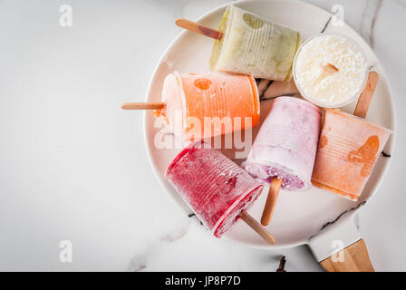 Gesunden Sommer Desserts. Eis Eis am Stiel. Gefrorene tropische Säfte, Smoothies Blaubeeren. Johannisbeere, Orange, Mango, Kiwi, Banane, Kokos, Himbeere Stockfoto