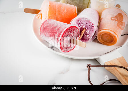 Gesunden Sommer Desserts. Eis Eis am Stiel. Gefrorene tropische Säfte, Smoothies Blaubeeren. Johannisbeere, Orange, Mango, Kiwi, Banane, Kokos, Himbeere Stockfoto
