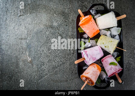 Gesunden Sommer Desserts. Eis Eis am Stiel. Gefrorene tropische Säfte, Smoothies Blaubeeren. Johannisbeere, Orange, Mango, Kiwi, Banane, Kokos, Himbeere Stockfoto
