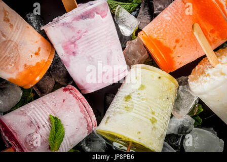 Gesunden Sommer Desserts. Eis Eis am Stiel. Gefrorene tropische Säfte, Smoothies Blaubeeren. Johannisbeere, Orange, Mango, Kiwi, Banane, Kokos, Himbeere Stockfoto