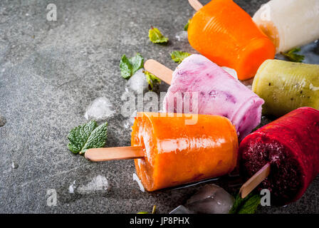 Gesunden Sommer Desserts. Eis Eis am Stiel. Gefrorene tropische Säfte, Smoothies Blaubeeren. Johannisbeere, Orange, Mango, Kiwi, Banane, Kokos, Himbeere Stockfoto