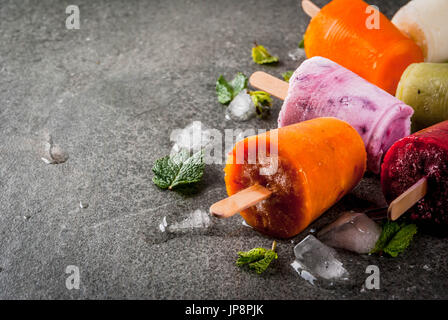 Gesunden Sommer Desserts. Eis Eis am Stiel. Gefrorene tropische Säfte, Smoothies Blaubeeren. Johannisbeere, Orange, Mango, Kiwi, Banane, Kokos, Himbeere Stockfoto