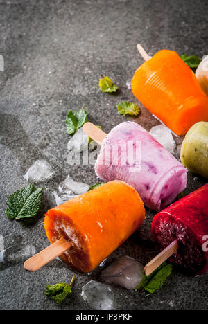 Gesunden Sommer Desserts. Eis Eis am Stiel. Gefrorene tropische Säfte, Smoothies Blaubeeren. Johannisbeere, Orange, Mango, Kiwi, Banane, Kokos, Himbeere Stockfoto