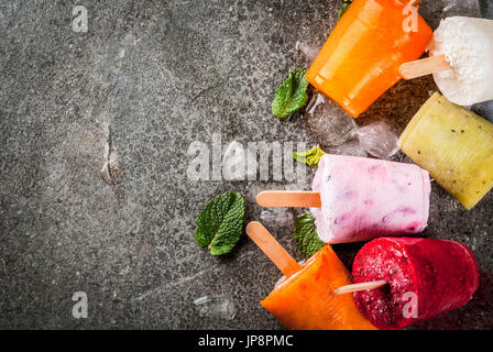 Gesunden Sommer Desserts. Eis Eis am Stiel. Gefrorene tropische Säfte, Smoothies Blaubeeren. Johannisbeere, Orange, Mango, Kiwi, Banane, Kokos, Himbeere Stockfoto