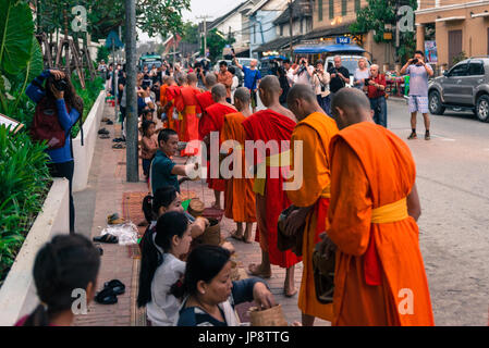 LUANG PRABANG, LAOS - MÄRZ 12, 2017: Horizontale Bild der Menschen vor Ort mit Essen und Geld zu den Mönchen für die Buddhistische Almosen Preisverleihung, in Stockfoto