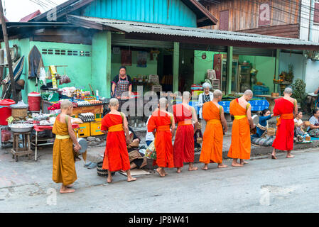 LUANG PRABANG, LAOS - MÄRZ 12, 2017: Weitwinkel Bild der Menschen vor Ort mit Essen und Geld zu den Mönchen für die Buddhistische Almosen Preisverleihung, in Stockfoto