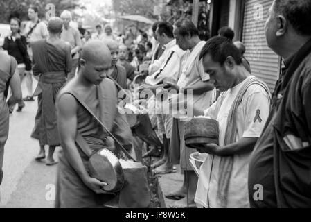 LUANG PRABANG, LAOS - MÄRZ 12, 2017: Schwarzweiß-Bild mit der Bewegung der Menschen vor Ort mit Essen und Geld zu den Mönchen für die Buddhistische Almosen G Stockfoto