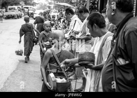 LUANG PRABANG, LAOS - MÄRZ 12, 2017: Schwarz-weiss Bild der Menschen vor Ort mit Essen und Geld zu den Mönchen für die Buddhistische Almosen Preisverleihung Stockfoto