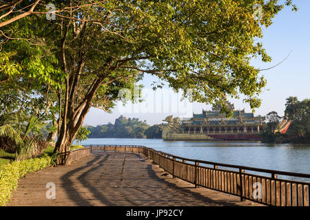 Der Holzsteg, üppige Bäume und Karaweik-halle Folgen am Kandawgyi See in Yangon, an einem sonnigen Tag Myanmar. Stockfoto