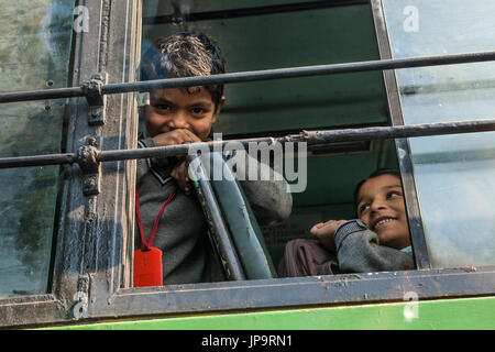 Ein Junge in das offene Fenster eines Schulbusses, Delhi, Indien. Stockfoto