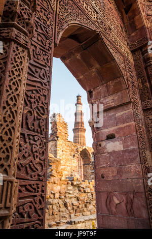 Qutb Minar umrahmt von einem Spitzer Torbogen im Qutb-Komplex Ruinen, Delhi, Indien. Stockfoto